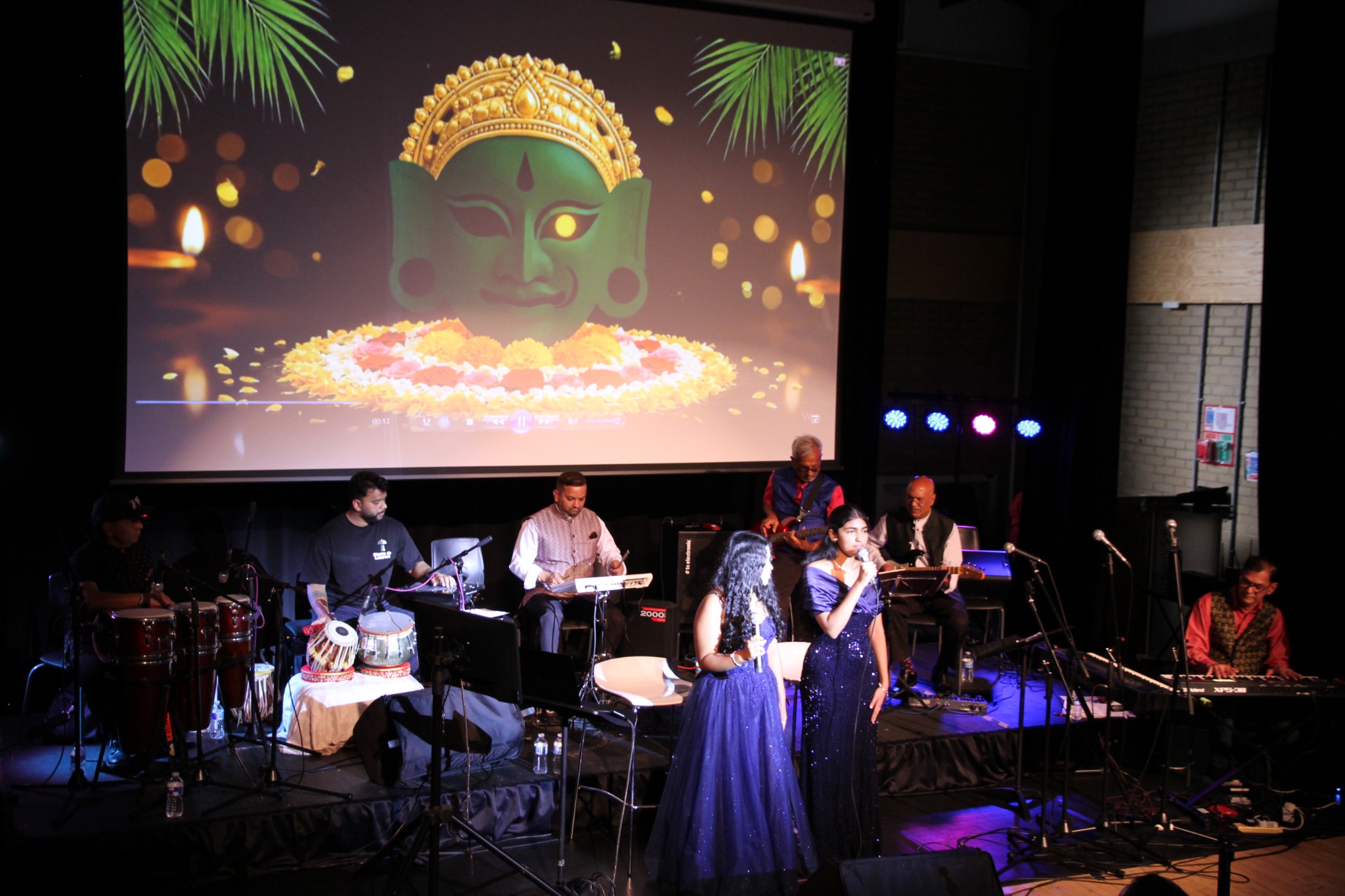 Musicians and singer on stage beneath colourful lights